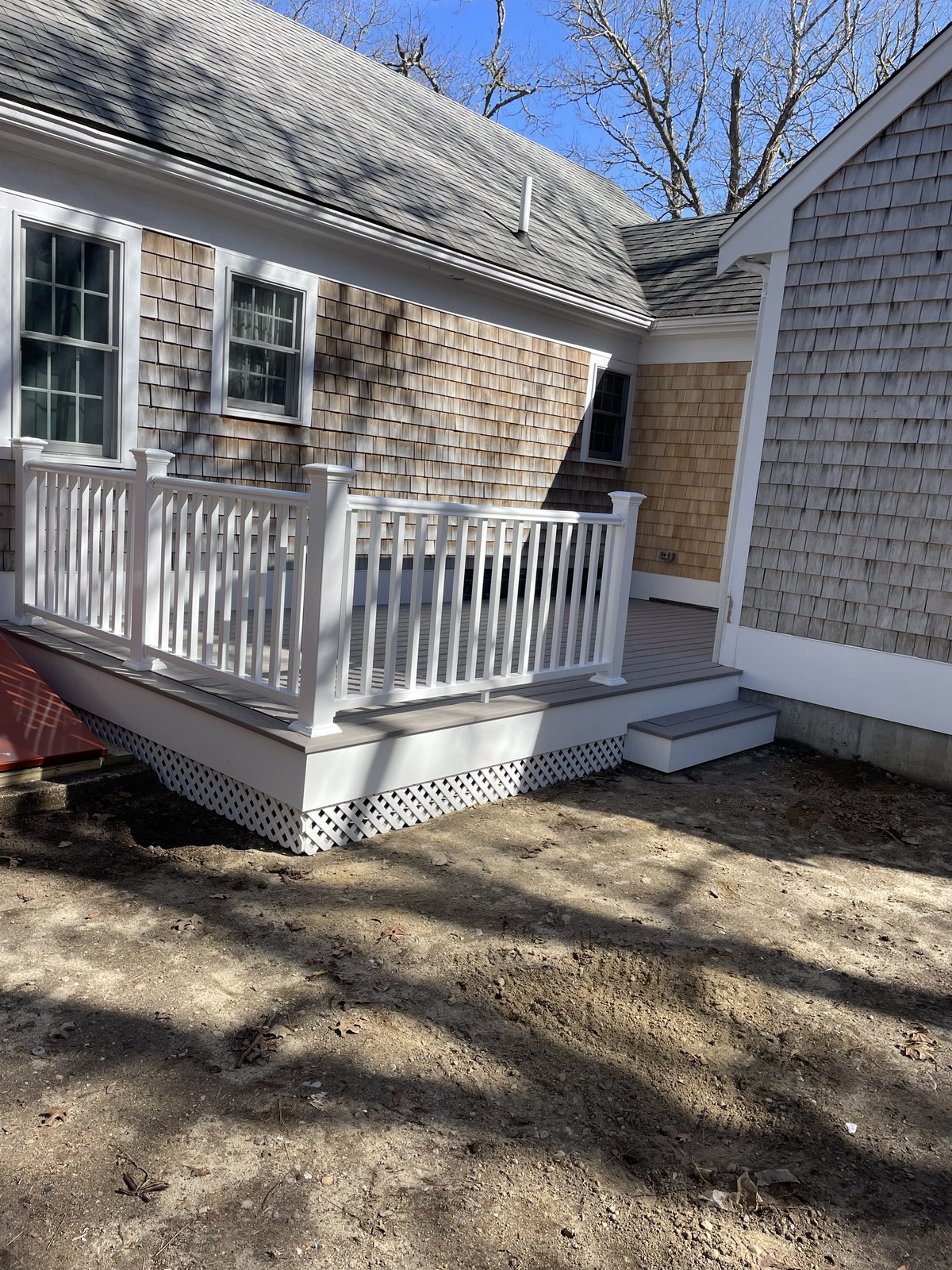 Farmers porch with white spindle railing and lattice skirt on a cedar-shingle home built by Perocchi Building & Remodeling, South Shore MA